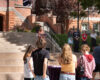 President Beth Dobkin stands behind a lectern on the stairs in front of Converse Hall while contributors to this partnership stand beside her to the right.
